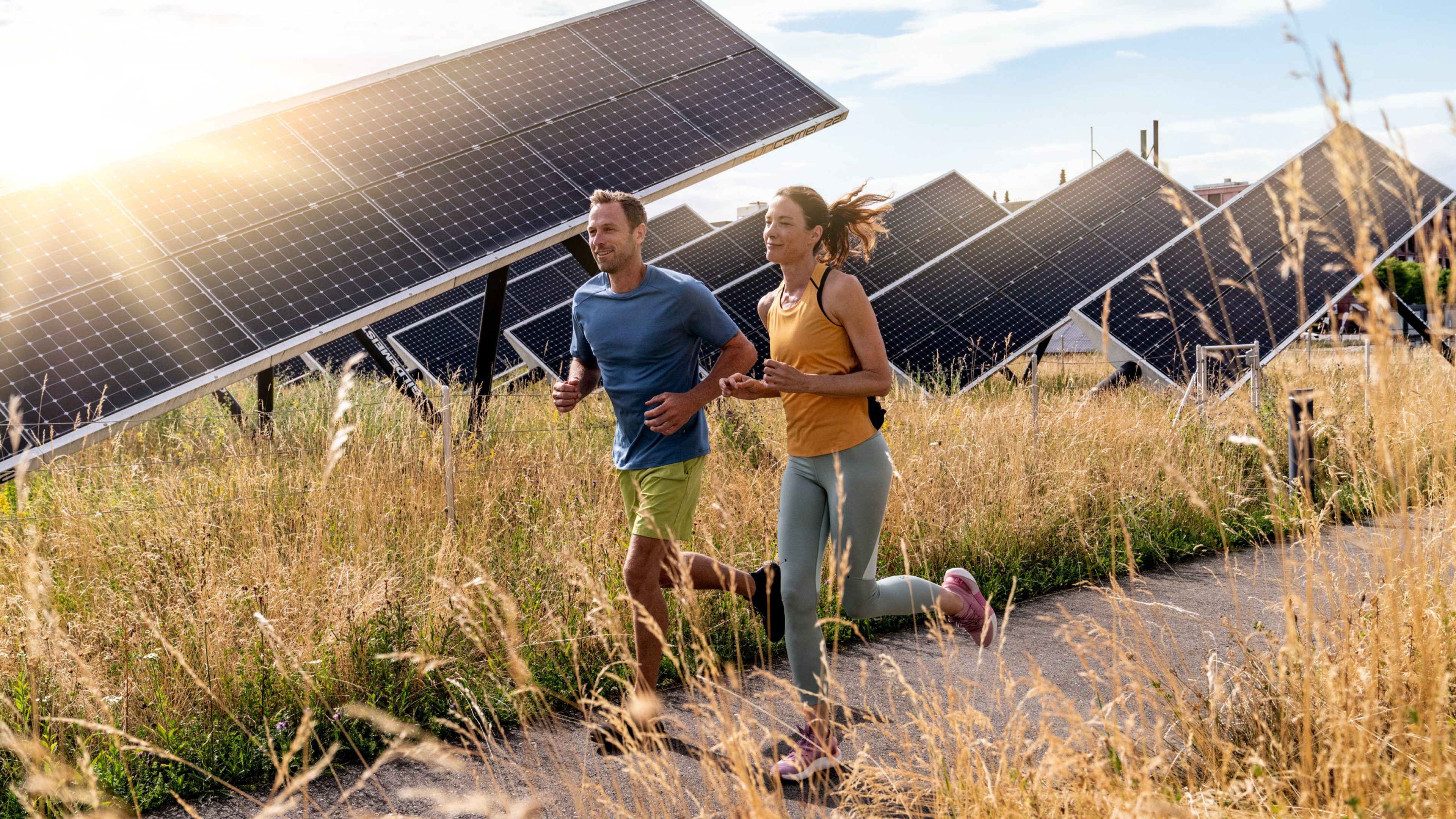 A couple jogging across a field with solar panels